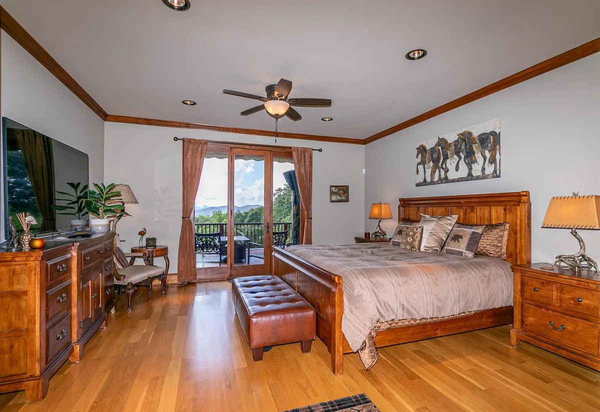 A cozy bedroom featuring a large wooden bed, soft bedding, and balcony doors that promise direct access outdoors. Artwork of horses adds a touch of rustic elegance, and the inviting space is perfect for morning coffee or stargazing evenings.